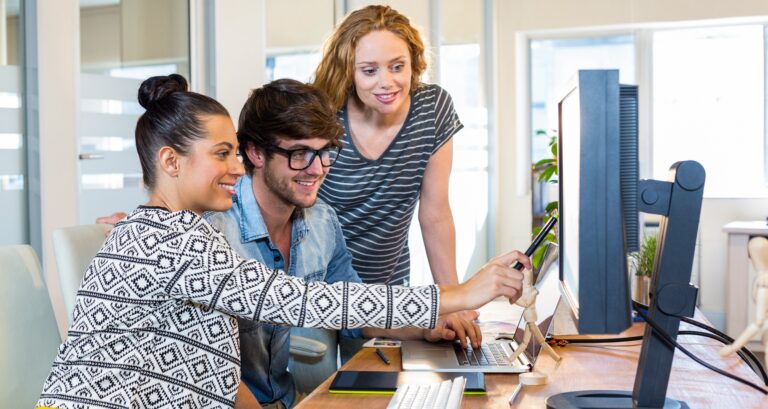 Drei junge Menschen arbeiten zusammen vor einem Bildschirm