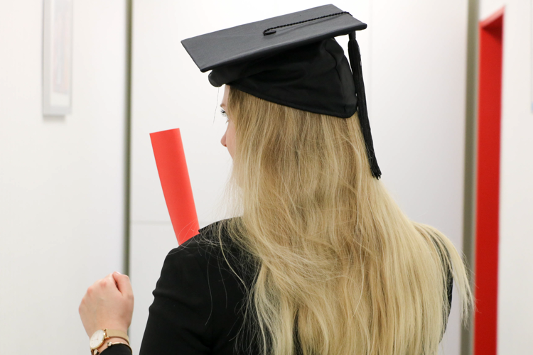 Frau mit schwarzen Doktorhut und Zertifikat in der Hand