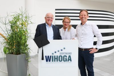 Gemeinsames Foto mit Frau Huchthausen, Herr Rohde und Herr Becker vor einem WIHOGA Rednerpult